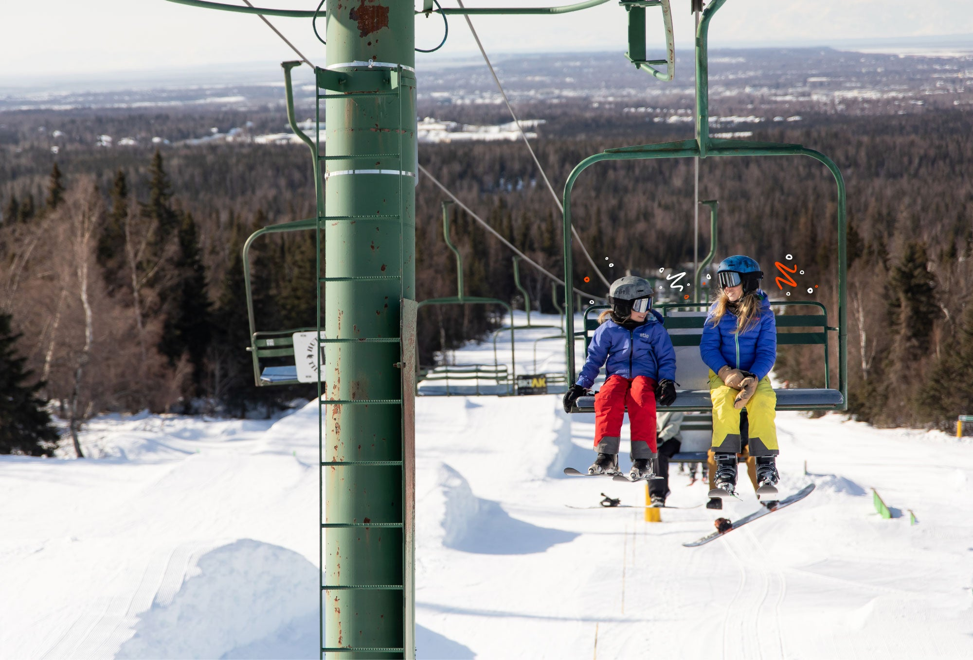 two kids riding a ski lift with tree and snowy landscape in background