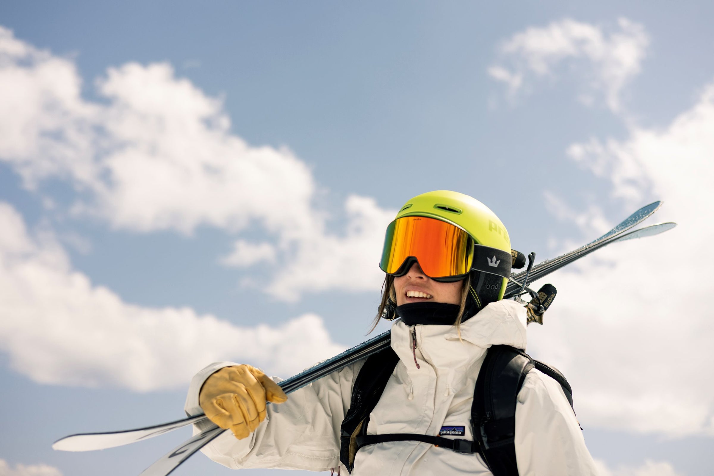 Person in ski gear with skis and helmet against a blue sky