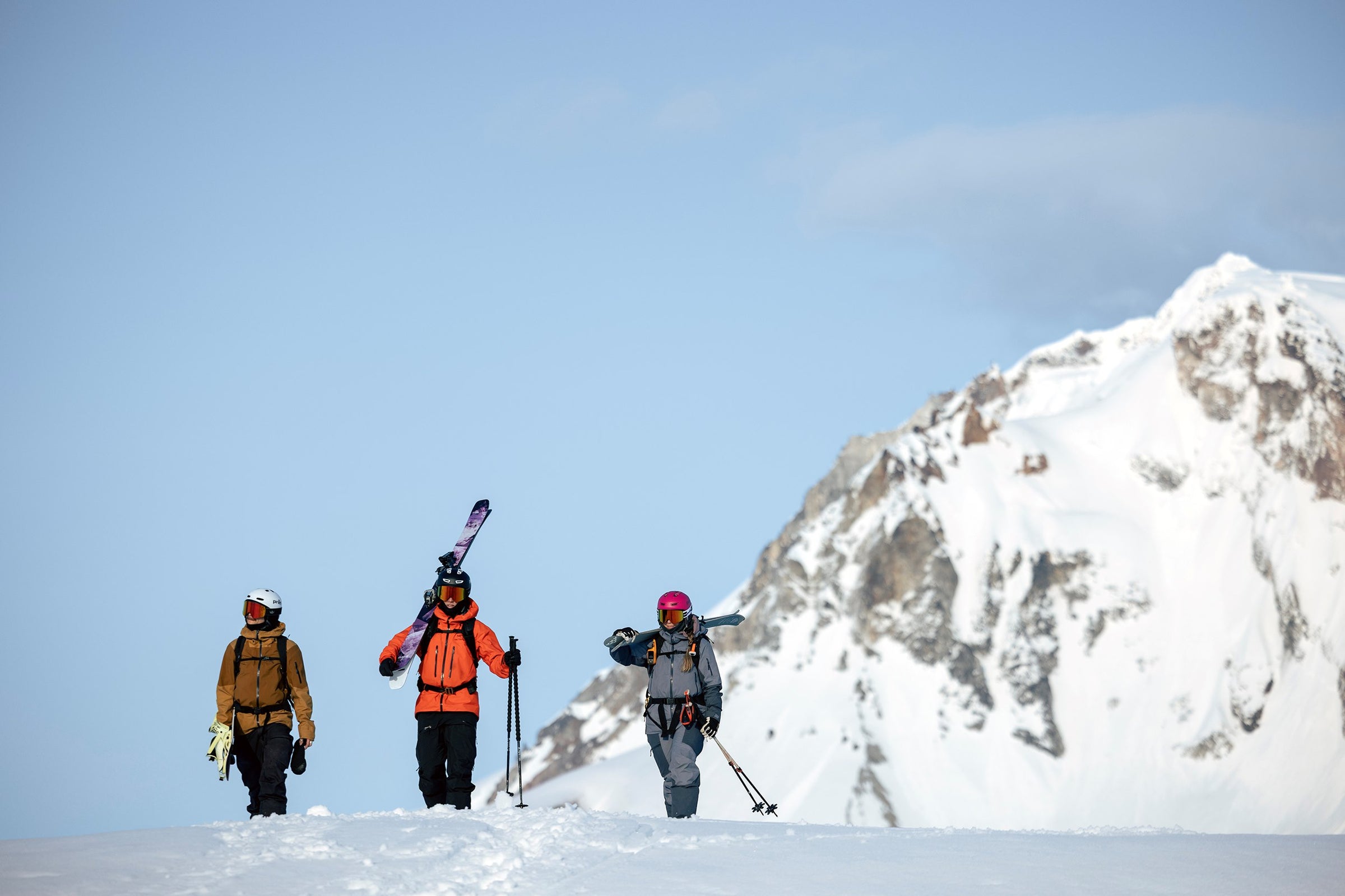 Three skiers on a snowy mountain with a clear blue sky