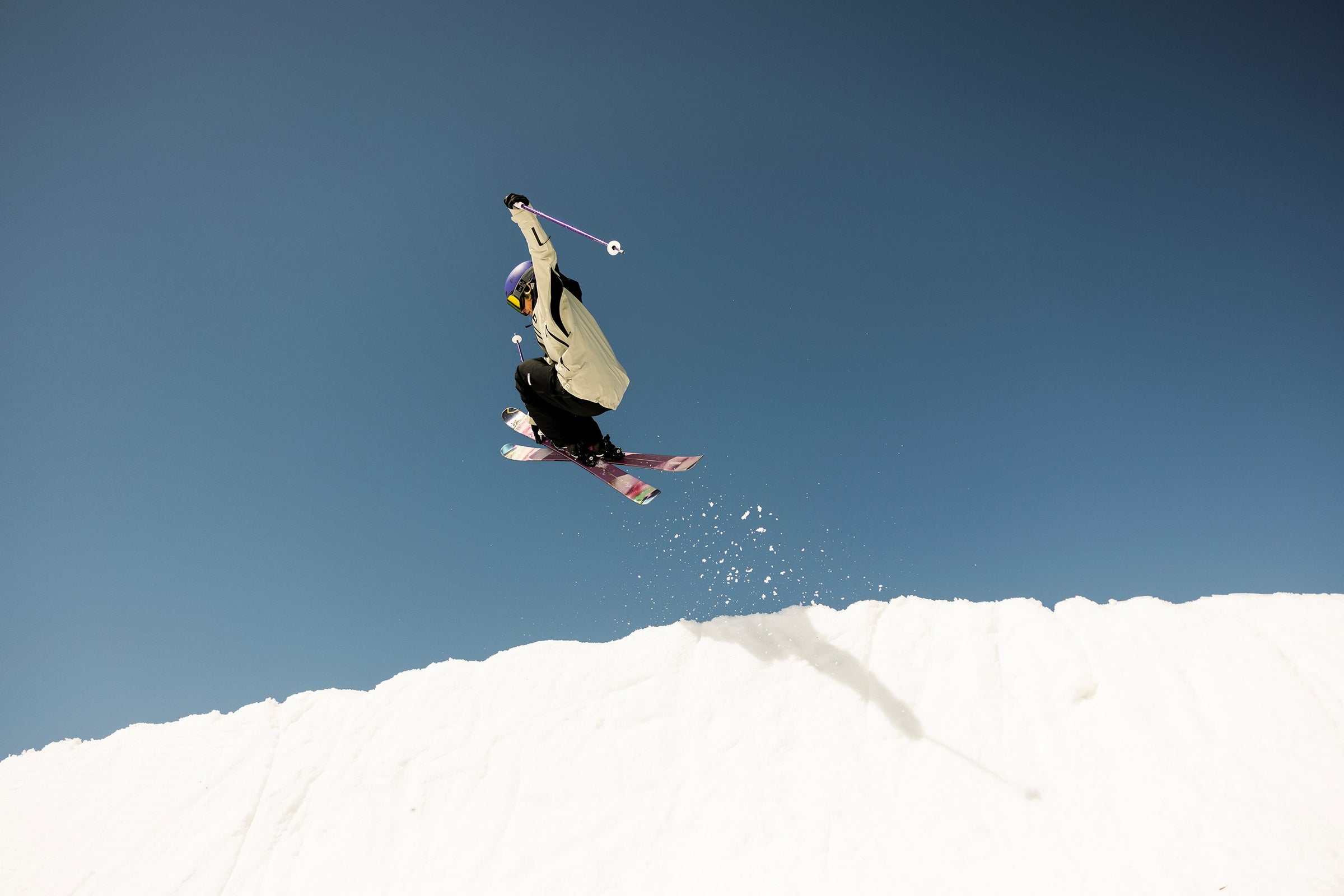 Skier performing a jump against a clear blue sky