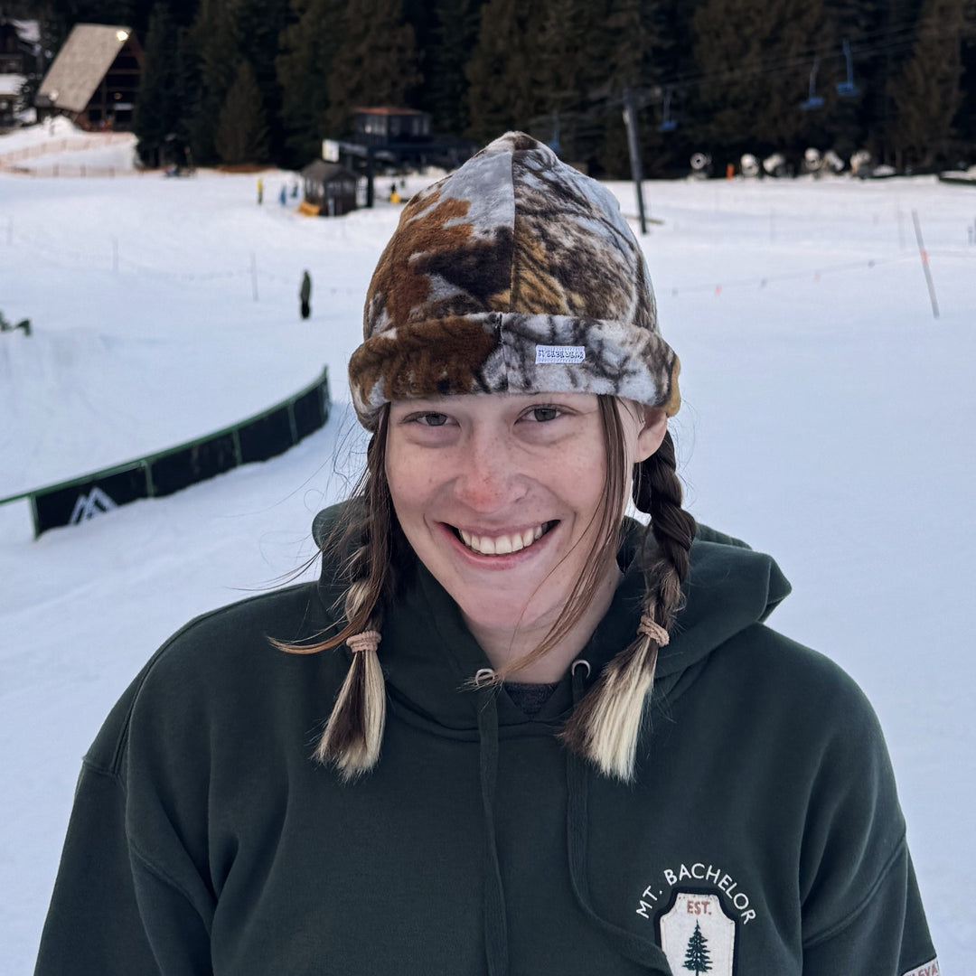 Christina Anderson wearing a camouflage hat and green hoodie with a logo at a ski resort