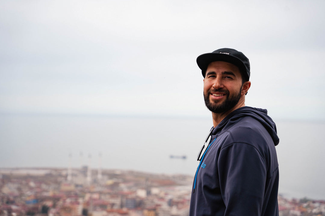 Giray Dadali wearing a cap and hoodie with a cityscape in the background