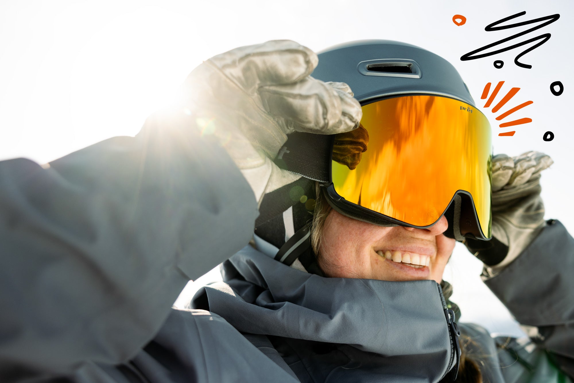 Person wearing a helmet with orange goggles, smiling outdoors.