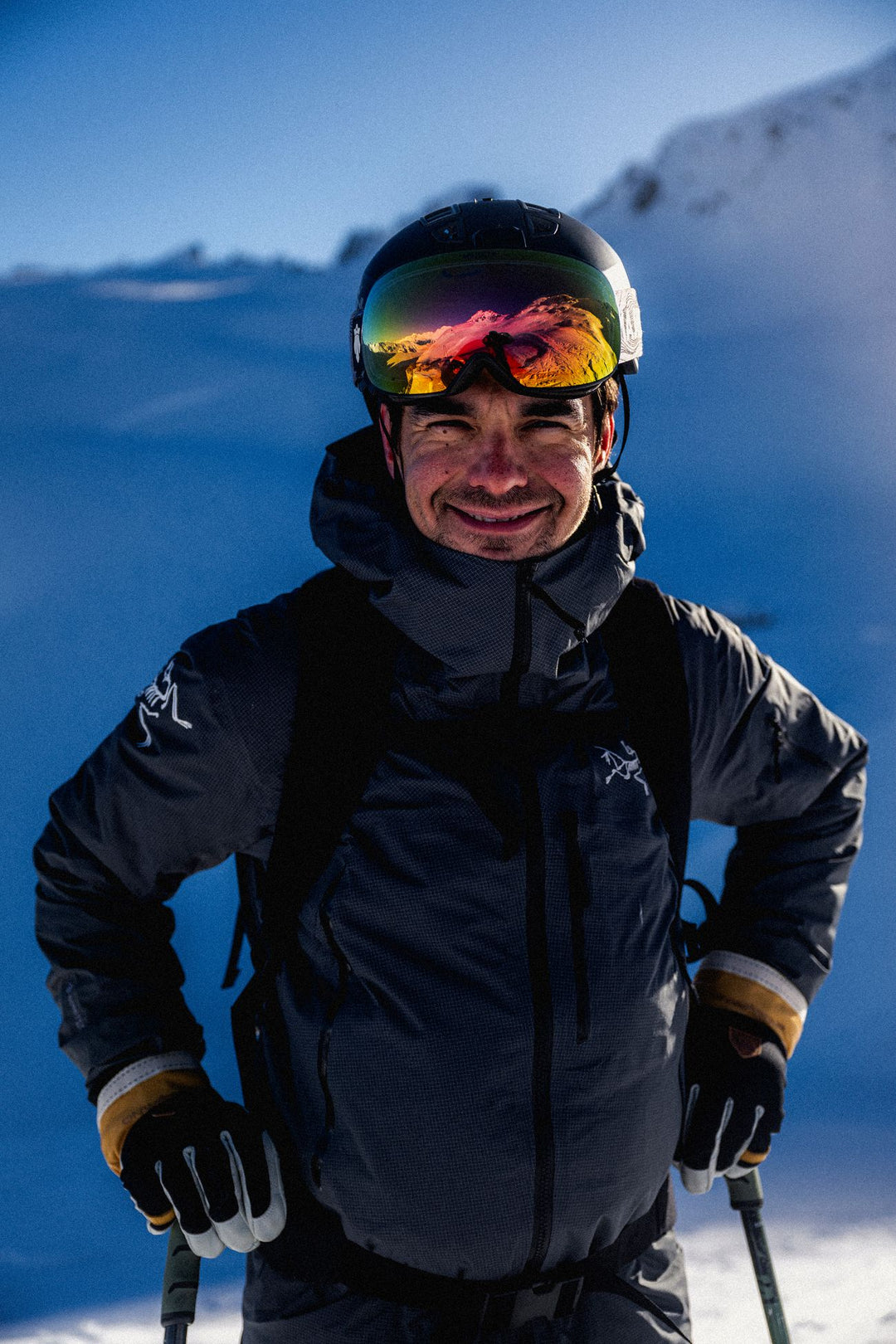 Person in ski gear with colorful goggles against a snowy mountain background